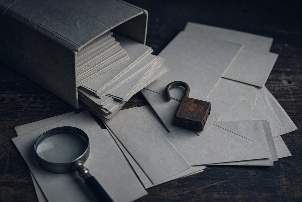 Boîte en carton, enveloppes, cadenas rouillé ouvert et loupe sur table
