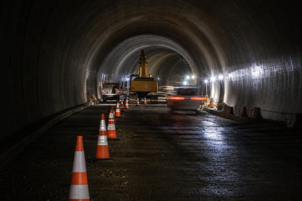 Tunnel routier en travaux avec cônes de signalisation orange et éclairage de chantier.