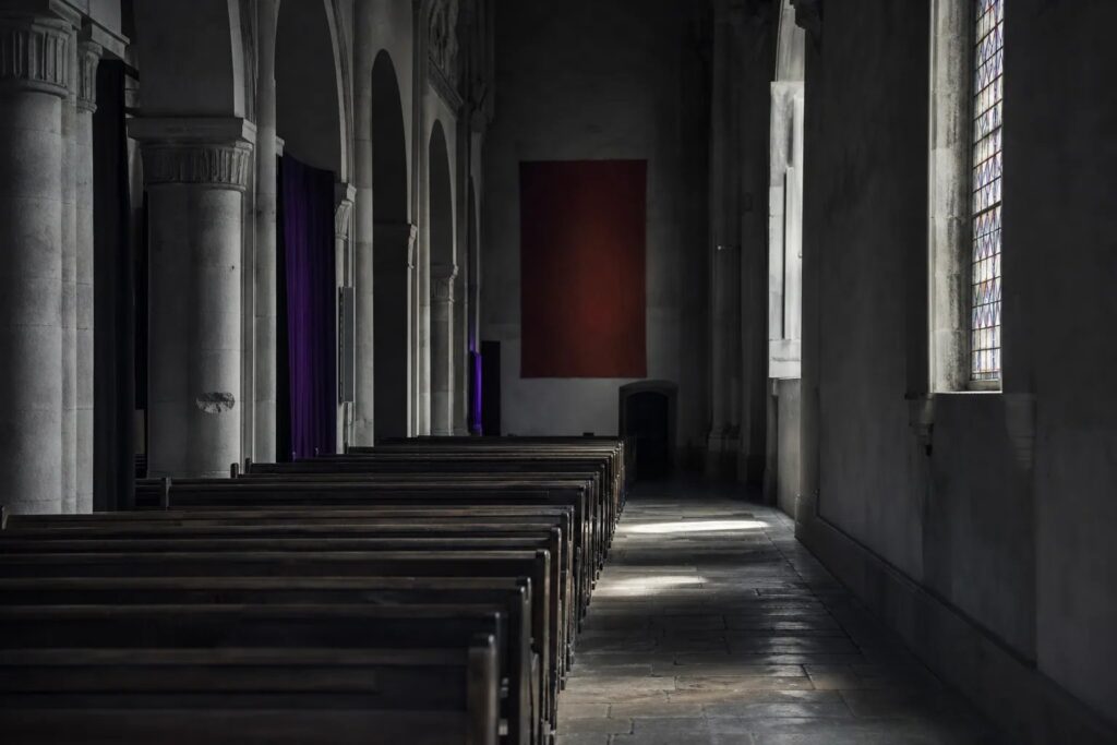 Nef d'église vide éclairée par un vitrail latéral