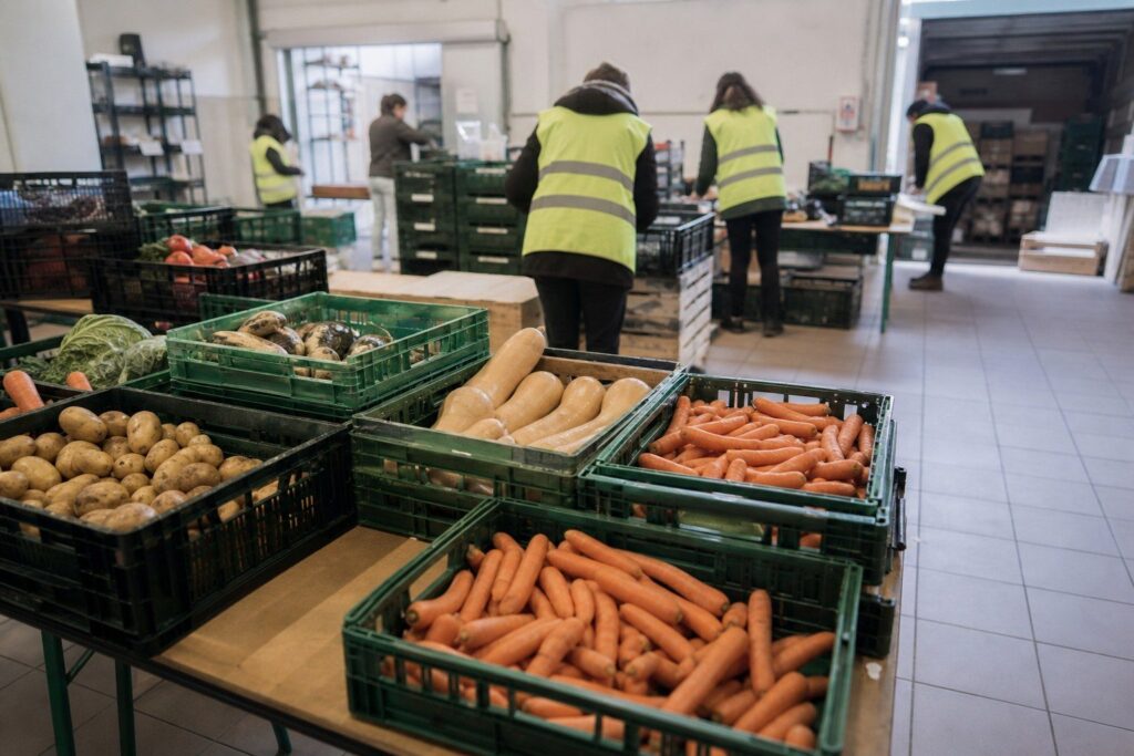 Bénévoles en gilets de sécurité triant des légumes dans un entrepôt de distribution alimentaire.