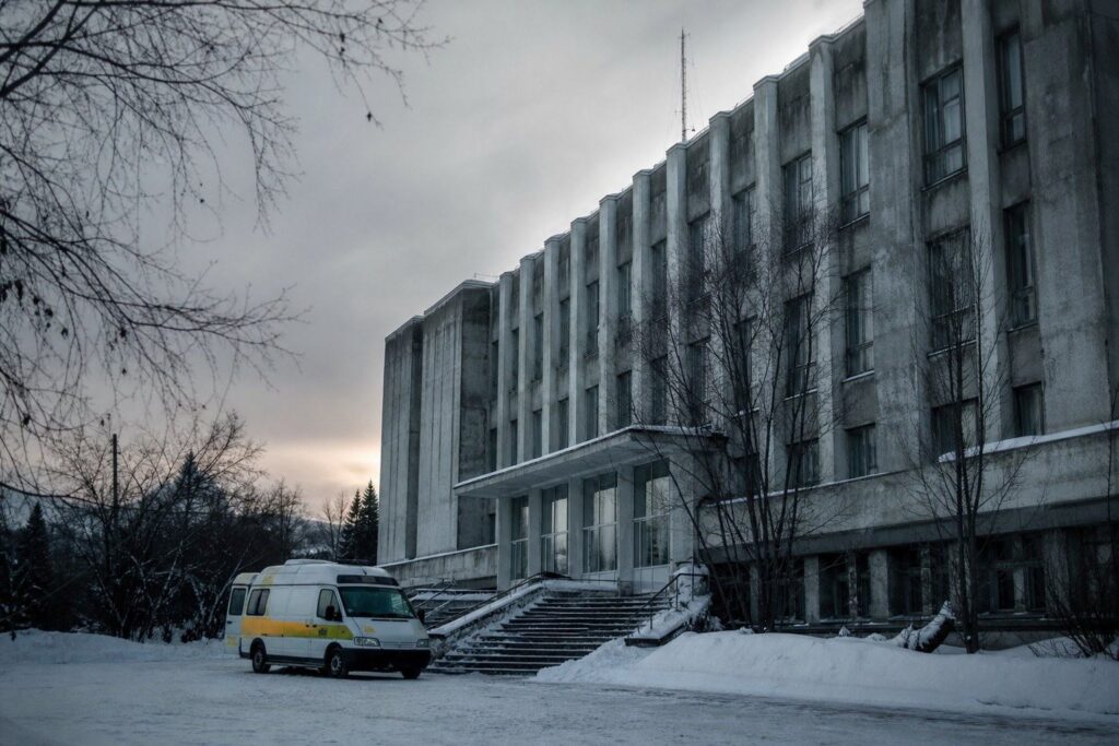 Bâtiment en béton enneigé avec une ambulance garée devant
