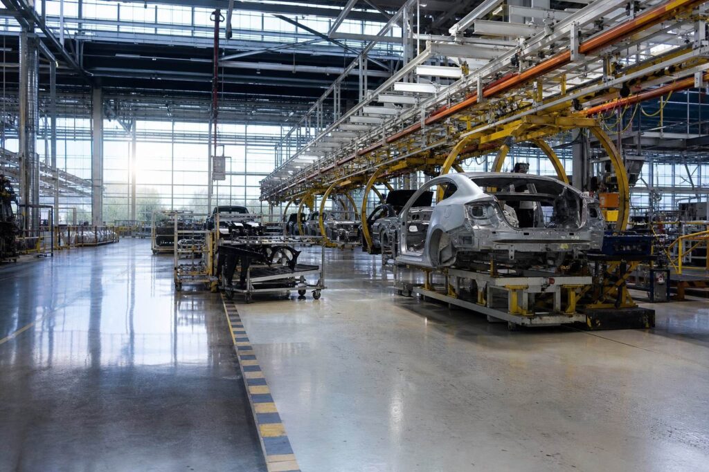 Chaîne de montage automobile, carrosseries de voitures en cours d'assemblage dans une usine éclairée.