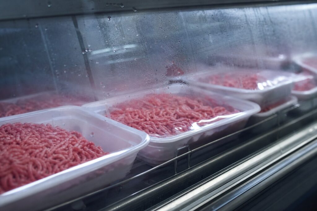 Barquettes de viande hachée sous film plastique dans une vitrine réfrigérée